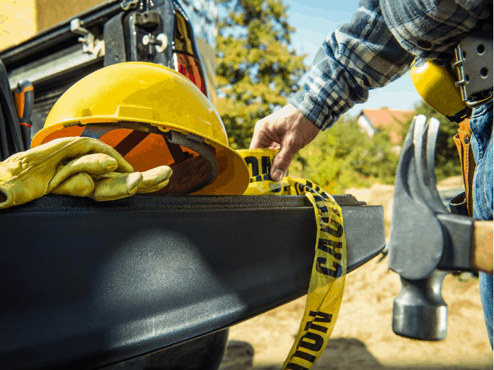 Construction worker grabs safety gear out of truck bed to prevent construction injuries at worksite
