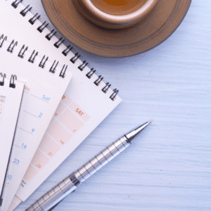 stack of calendars lie next to pen and a coffee cup as person looks over them to schedule their meeting with persoanl injury lawyer