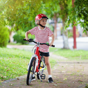 Kid wearing helmet rides his bike to school