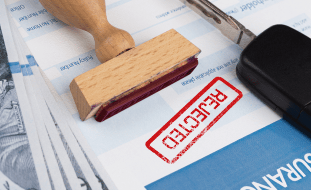 A stamp lies on top of insurance paperwork after an insurance agent rejects their clients insurance claim