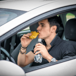 man distracted because he is eating and drinking while driving
