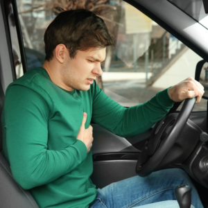 man clutches chest and worries he's having a heart attack while driving
