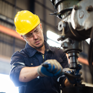 Factory worker repairing machinery, highlighting safety precautions and the importance of proper training.