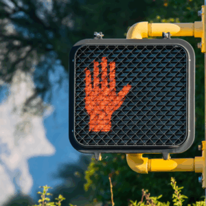 A no-walking signal at a crosswalk that would be missed if a pedestrian was looking at their phone, highlighting the dangers of distracted walking.